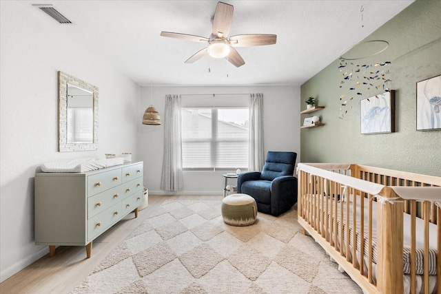8848 Sunlit Cove Dr NE, Saint Petersburg, FL 33702 - bedroom with a nursery area, a ceiling fan, and light wood finished floors