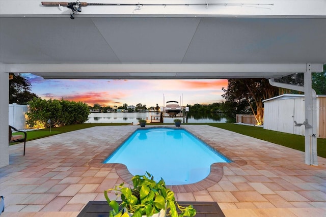 8848 Sunlit Cove Dr NE, Saint Petersburg, FL 33702 - pool at dusk with boat lift, a patio area, a water view, and a boat dock