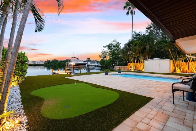 8848 Sunlit Cove Dr NE, Saint Petersburg, FL 33702 - view of swimming pool with an area to practice putting, a patio area, boat lift, a fenced backyard, and a water view