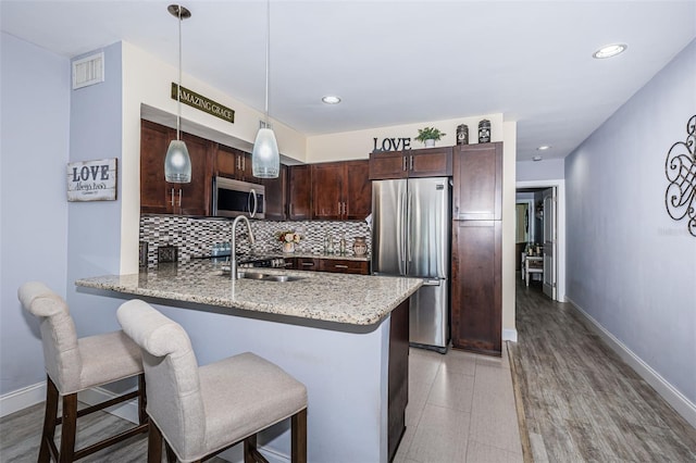 5694 40th Ter N Unit 423, Kenneth City, FL 33709 - kitchen featuring appliances with stainless steel finishes, dark brown cabinets, a peninsula, backsplash, and light stone counters