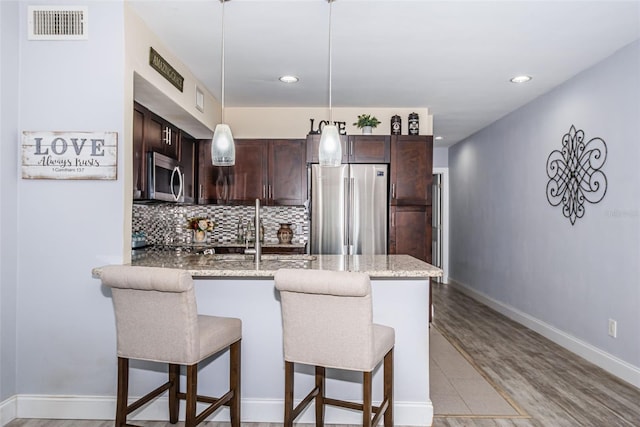 5694 40th Ter N Unit 423, Kenneth City, FL 33709 - kitchen with stainless steel appliances, a peninsula, dark brown cabinetry, recessed lighting, and a kitchen breakfast bar