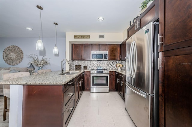 5694 40th Ter N Unit 423, Kenneth City, FL 33709 - kitchen featuring appliances with stainless steel finishes, a sink, light stone countertops, tasteful backsplash, and a kitchen bar