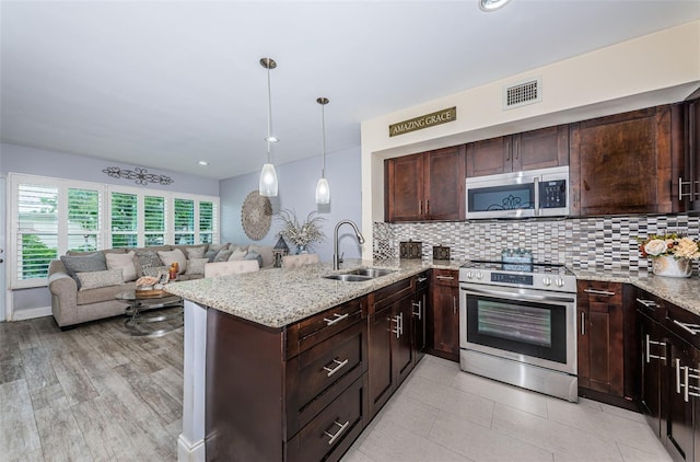 5694 40th Ter N Unit 423, Kenneth City, FL 33709 - kitchen featuring appliances with stainless steel finishes, a sink, open floor plan, dark brown cabinets, and light stone counters