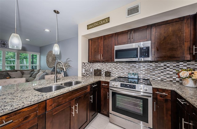 5694 40th Ter N Unit 423, Kenneth City, FL 33709 - kitchen with stainless steel appliances, a sink, light stone countertops, decorative backsplash, and light tile patterned floors
