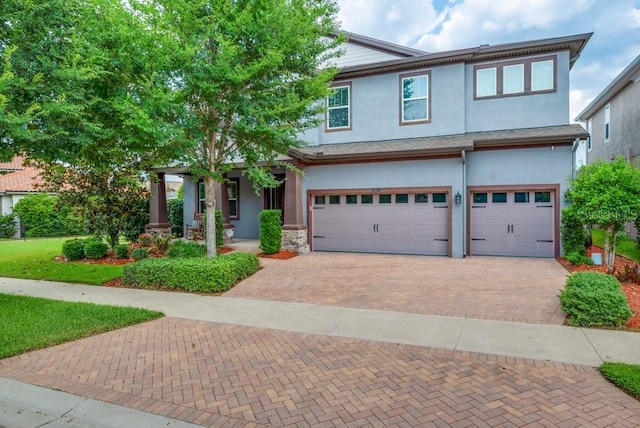 multi unit property with decorative driveway, a garage, stucco siding, and a porch