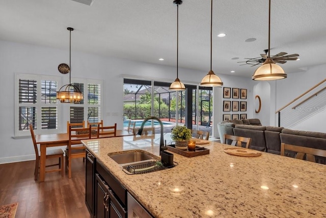 kitchen featuring a sink, dark wood-type flooring, open floor plan, pendant lighting, and a ceiling fan