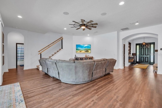 living room with arched walkways, wood finished floors, a ceiling fan, stairway, and recessed lighting