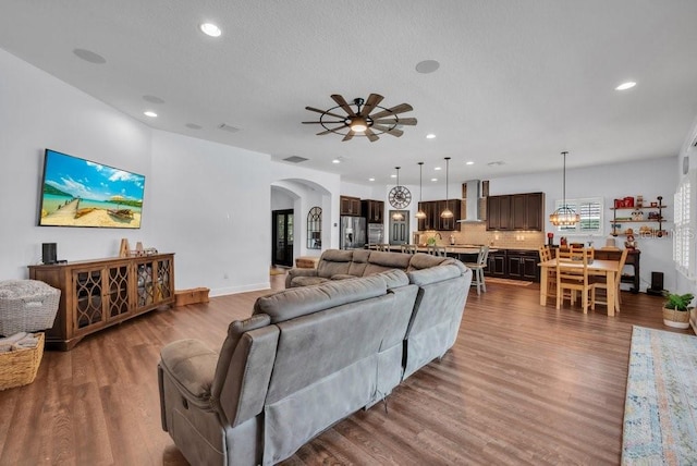 living area with arched walkways, a ceiling fan, recessed lighting, wood finished floors, and baseboards