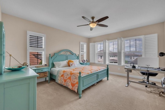 bedroom with light carpet, an office area, baseboards, and a ceiling fan