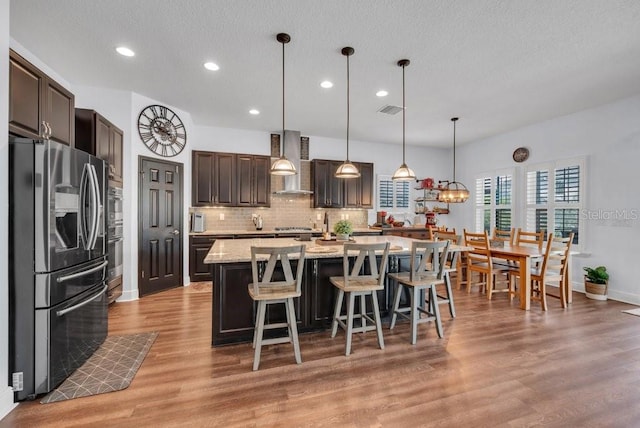 5724 Shell Ridge Dr, Lithia, FL 33547 - kitchen featuring stainless steel appliances, wall chimney range hood, recessed lighting, decorative backsplash, and light wood-type flooring