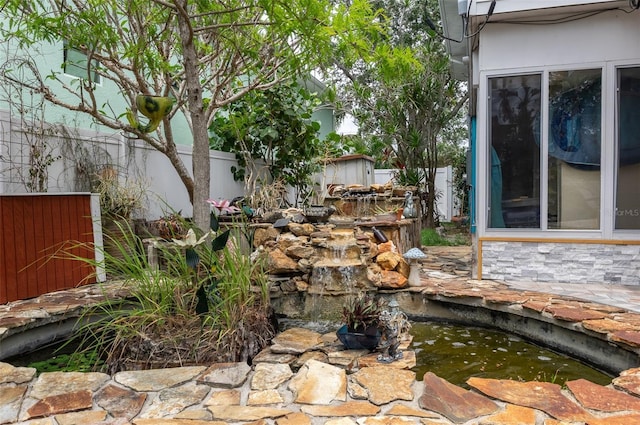854 77th Ave N, Saint Petersburg, FL 33702 - exterior view of a garden pond, fence, and stone siding