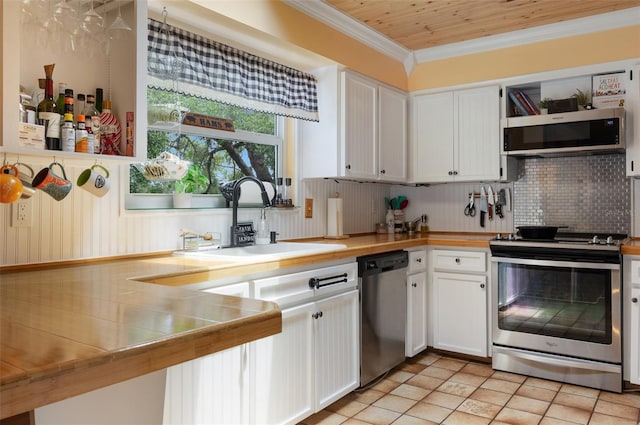 854 77th Ave N, Saint Petersburg, FL 33702 - kitchen featuring stainless steel appliances, a sink, white cabinetry, decorative backsplash, and ornamental molding
