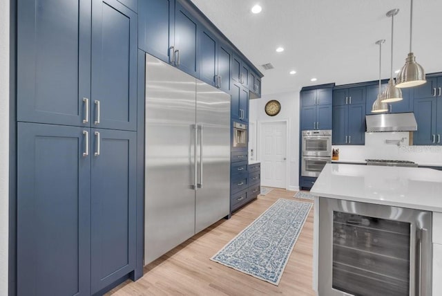 5507 Keeler Oak St, Lithia, FL 33547 - kitchen with appliances with stainless steel finishes, wine cooler, under cabinet range hood, blue cabinetry, and recessed lighting