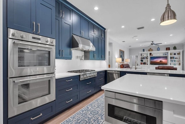 5507 Keeler Oak St, Lithia, FL 33547 - kitchen with stainless steel appliances, blue cabinets, under cabinet range hood, and recessed lighting