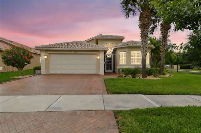 16101 Cape Coral Dr, Wimauma, FL 33598 - mediterranean / spanish-style house with decorative driveway, stucco siding, a front yard, and a garage