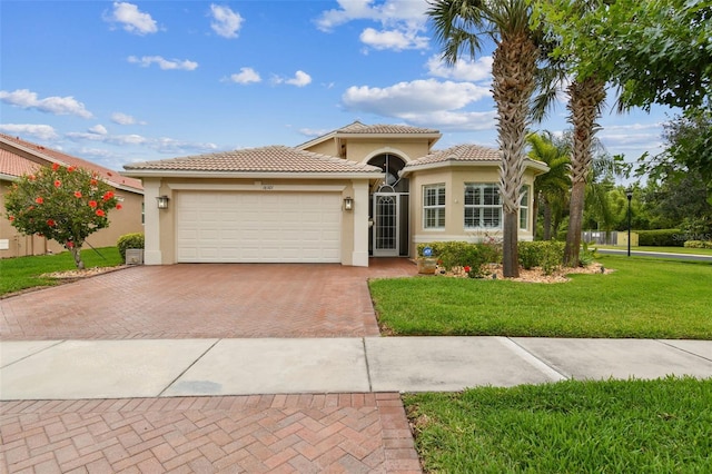 16101 Cape Coral Dr, Wimauma, FL 33598 - mediterranean / spanish-style home featuring stucco siding, decorative driveway, a front lawn, an attached garage, and a tiled roof