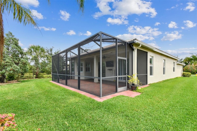 16101 Cape Coral Dr, Wimauma, FL 33598 - rear view of property featuring a lawn, stucco siding, glass enclosure, and a ceiling fan