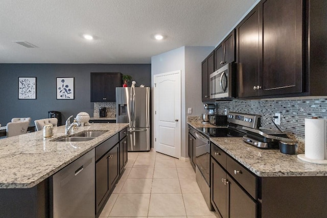 9532 Black Walnut Dr, Clermont, FL 34715 - kitchen featuring appliances with stainless steel finishes, a sink, tasteful backsplash, dark brown cabinetry, and light tile patterned floors