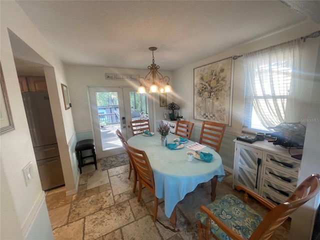 6073 115th Ave N, Pinellas Park, FL 33782 - dining space featuring stone tile flooring, french doors, a chandelier, and baseboards