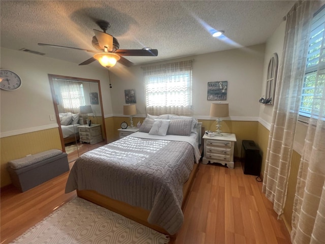6073 115th Ave N, Pinellas Park, FL 33782 - bedroom with multiple windows, wainscoting, light wood-type flooring, a textured ceiling, and ceiling fan