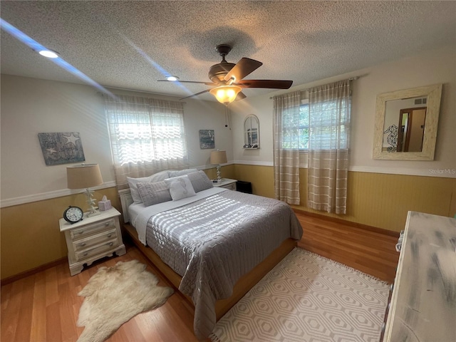 6073 115th Ave N, Pinellas Park, FL 33782 - bedroom featuring a wainscoted wall, wood finished floors, a textured ceiling, and ceiling fan