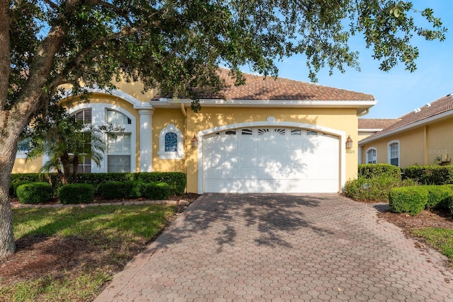 mediterranean / spanish home featuring stucco siding, decorative driveway, and a garage
