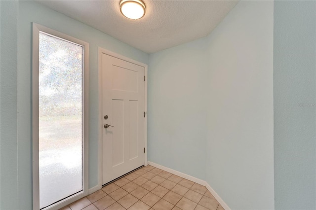 foyer with light tile patterned floors, a textured ceiling, and baseboards
