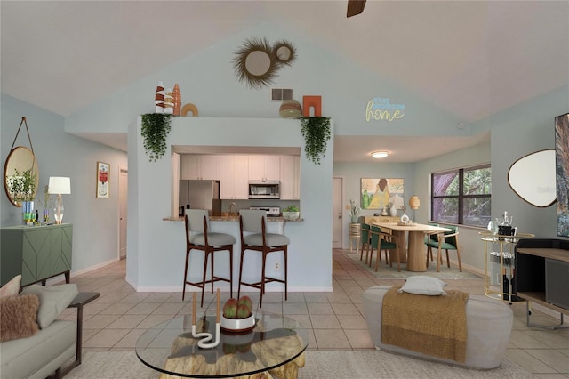 living room featuring high vaulted ceiling, light tile patterned floors, and baseboards