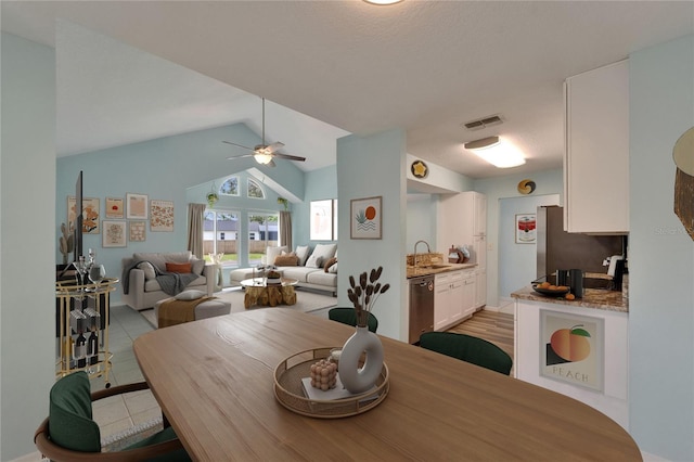 dining space with a ceiling fan, lofted ceiling, and light tile patterned floors