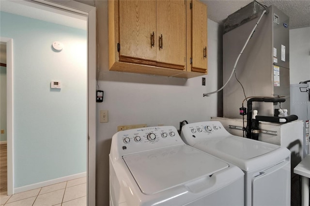 clothes washing area with cabinet space, independent washer and dryer, baseboards, and light tile patterned floors