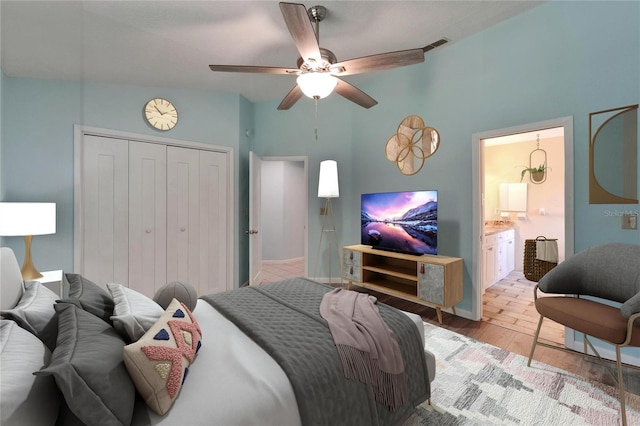 bedroom featuring light wood finished floors, a closet, a ceiling fan, and connected bathroom