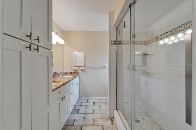 full bath with a shower stall, baseboards, and double vanity