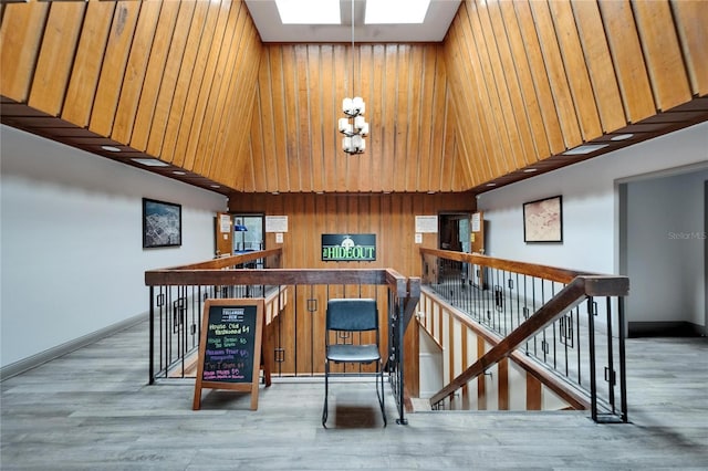 bar with a high ceiling, baseboards, a skylight, wood walls, and wood finished floors