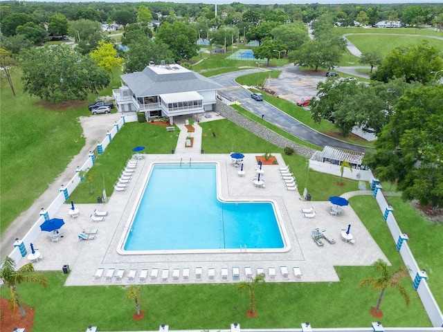 drone / aerial view of a pool and a tree filled landscape