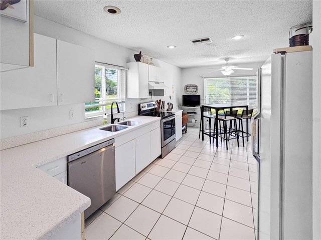 2413 Oxford Down Ct Unit 58, Sun City Center, FL 33573 - kitchen with stainless steel appliances, a sink, under cabinet range hood, light countertops, and white cabinets
