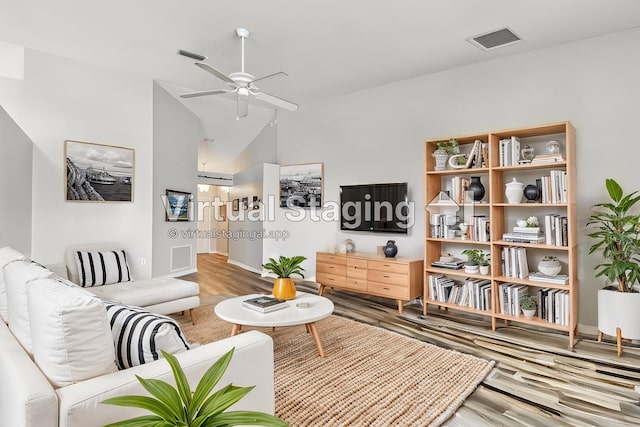living room featuring lofted ceiling, ceiling fan, wood finished floors, and baseboards