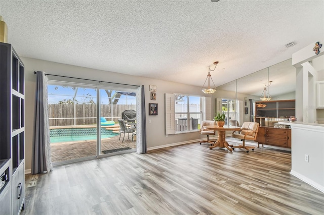 dining area with a textured ceiling, wood finished floors, plenty of natural light, and baseboards
