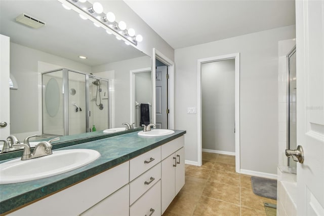 full bath with a stall shower, double vanity, tile patterned floors, and baseboards