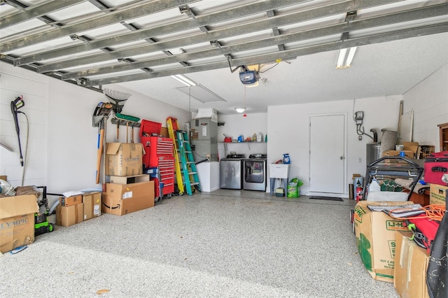 garage featuring independent washer and dryer, a garage door opener, and a sink