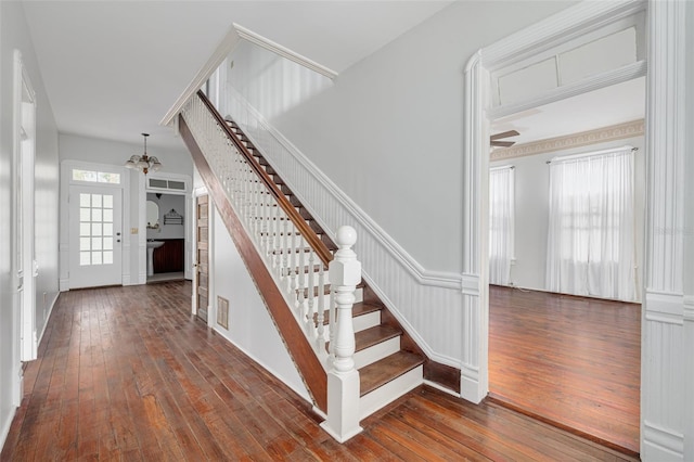 stairs featuring wood-type flooring and a chandelier