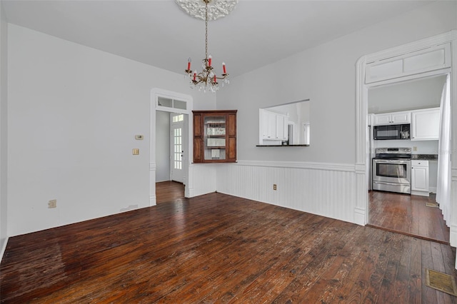 unfurnished living room featuring a chandelier and dark wood-style flooring