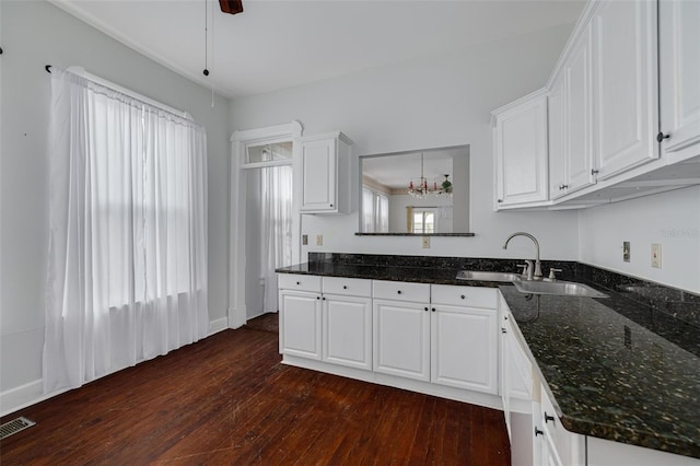 kitchen featuring a sink, dark wood finished floors, white cabinetry, dark stone countertops, and a ceiling fan