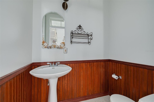 bathroom featuring a wainscoted wall, toilet, and wooden walls