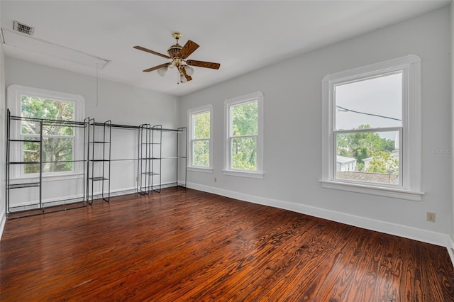 unfurnished room featuring attic access, dark wood-type flooring, baseboards, and ceiling fan