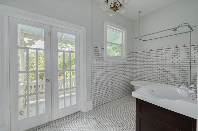 bathroom with tile walls, tile patterned flooring, wainscoting, vanity, and a chandelier
