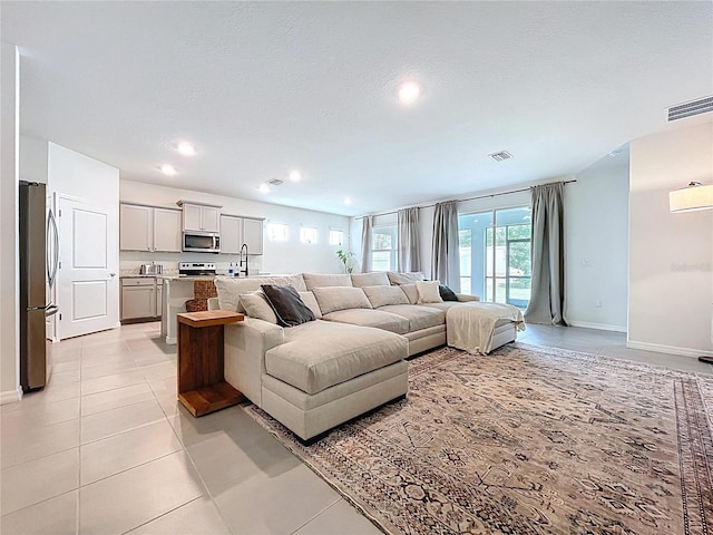 living area with baseboards, light tile patterned floors, and recessed lighting