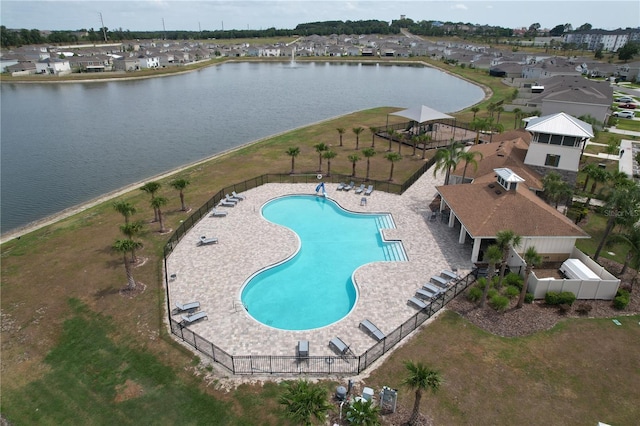 community pool with a water view, fence, and a residential view