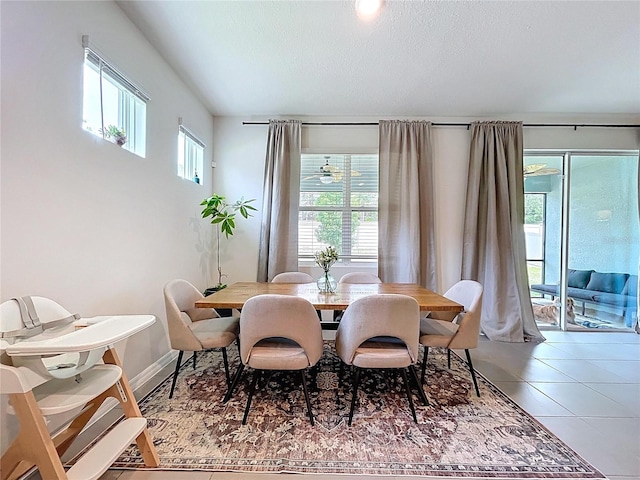 dining space featuring light tile patterned floors, baseboards, and a textured ceiling