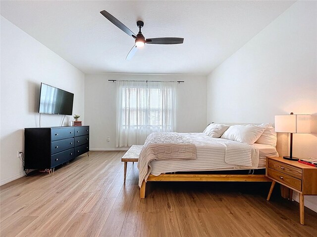 bedroom with light wood-type flooring, baseboards, and a ceiling fan