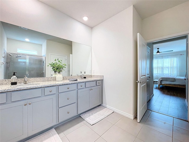 bathroom with a stall shower, double vanity, baseboards, ensuite bathroom, and tile patterned flooring